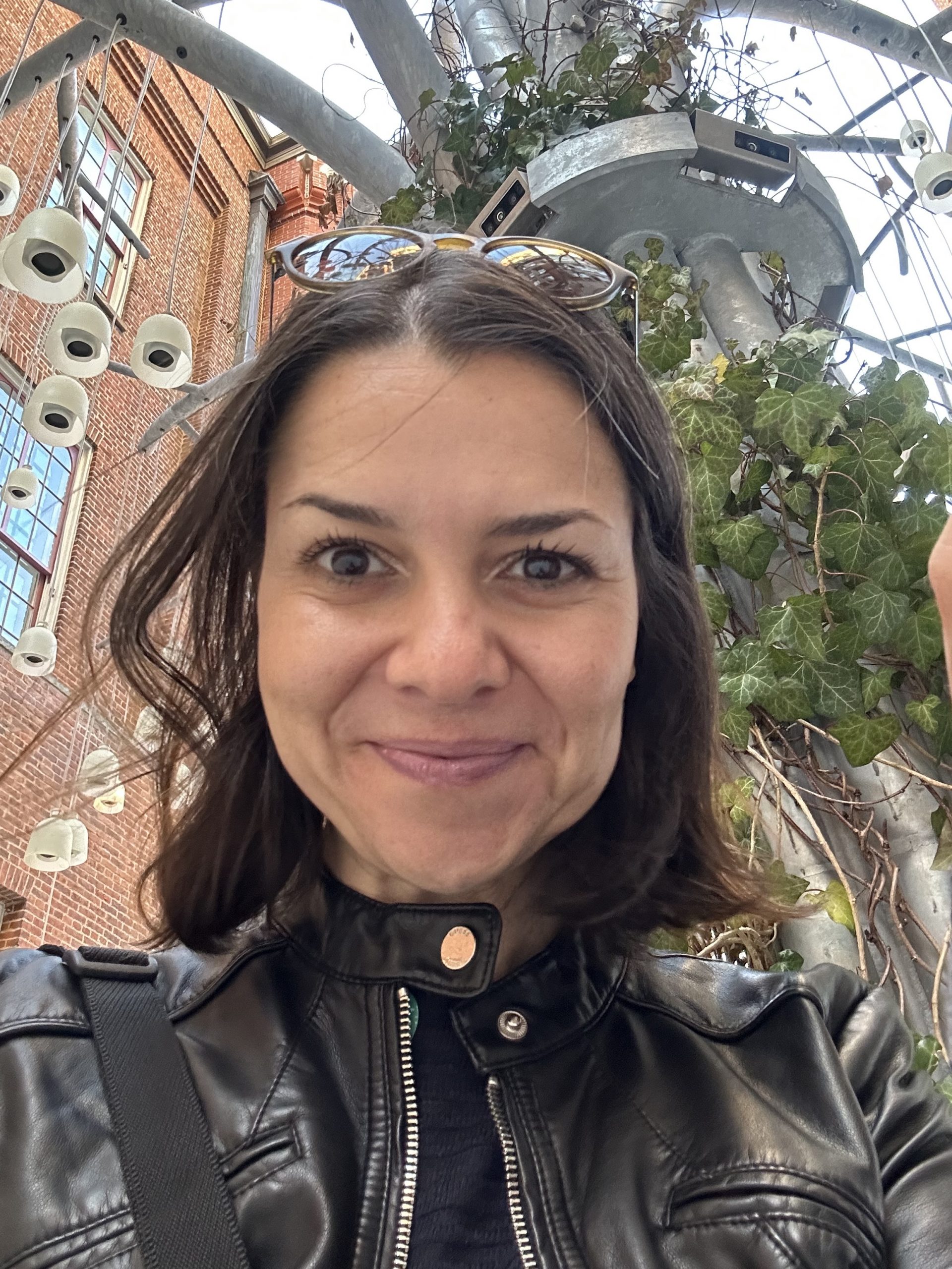 A picture of Burcu Kuheylan, a smiling woman wearing a black leather jacket.