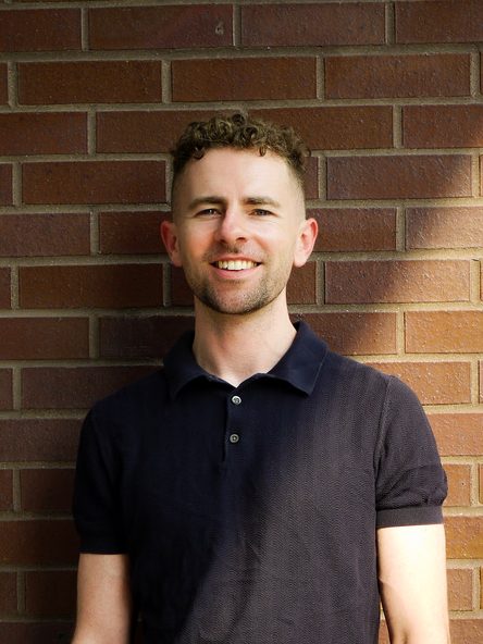 Thomas Conners smiling in a blue shirt.