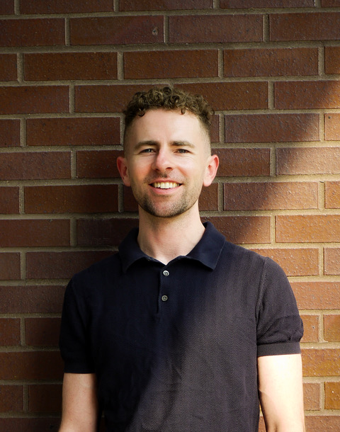 Thomas Conners smiling in a blue shirt.