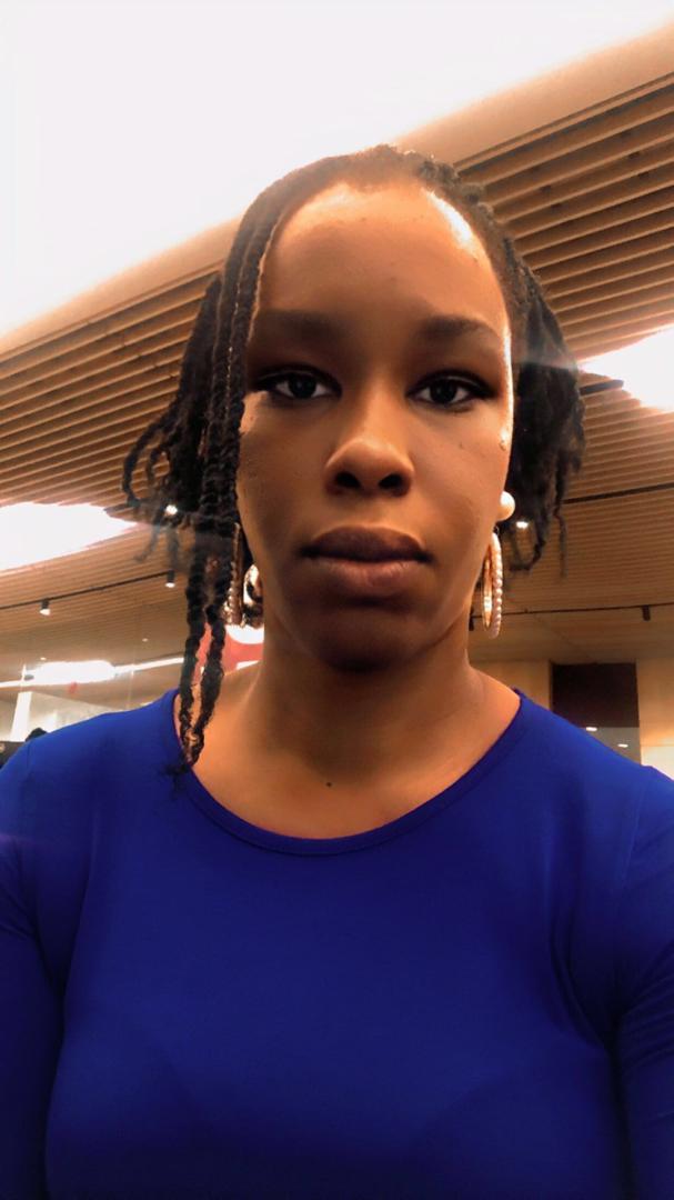 Adaobi Ejechi is wearing blue, with white earrings. They are looking directly into the camera.