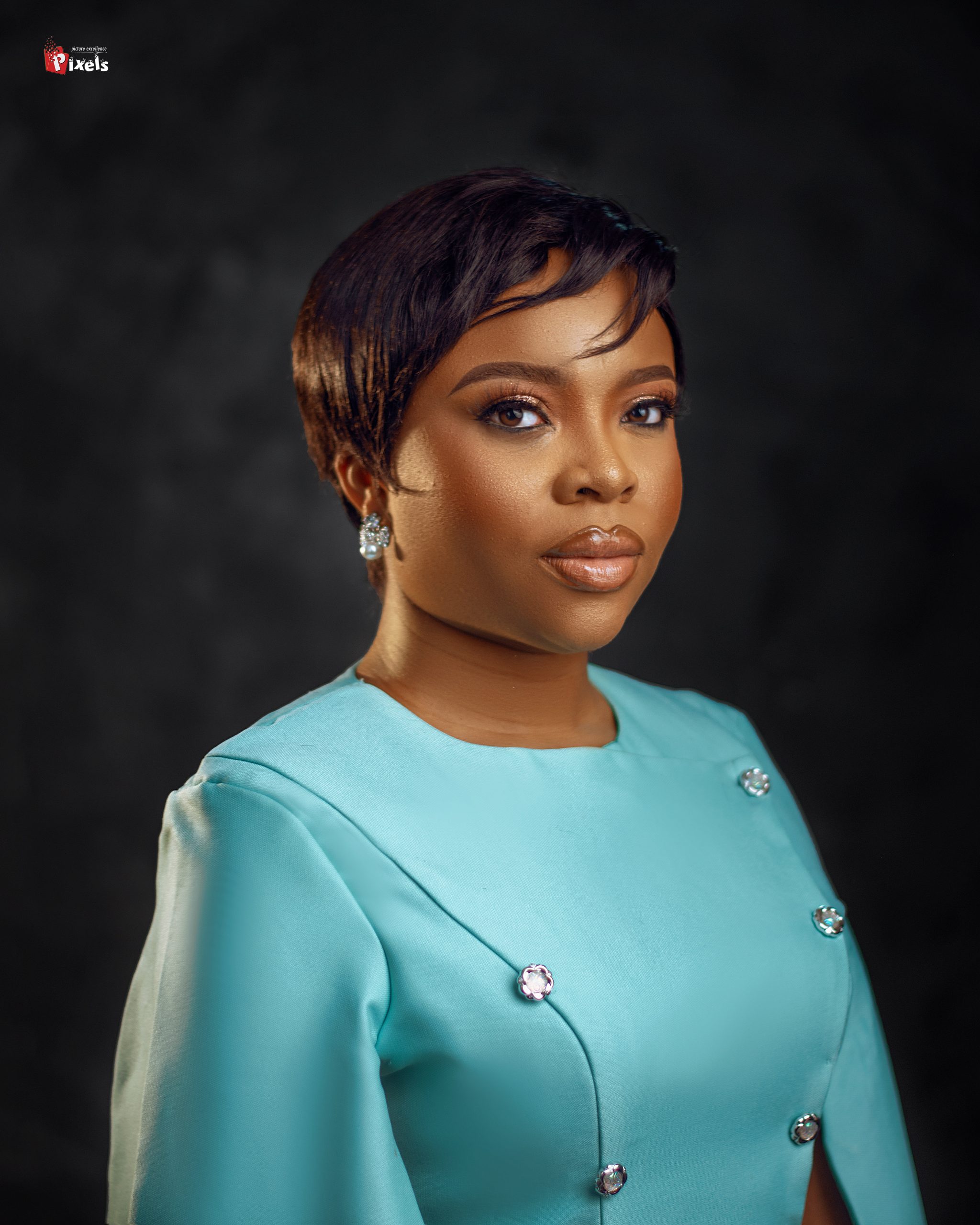 A headshot of Toluwani Odedeyis. She is wearing a light blue, structured top with crystal buttons and matching earrings. 